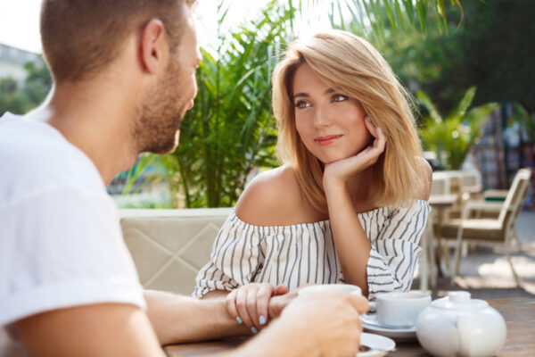 Cuplu discutând tandru la o cafenea în aer liber